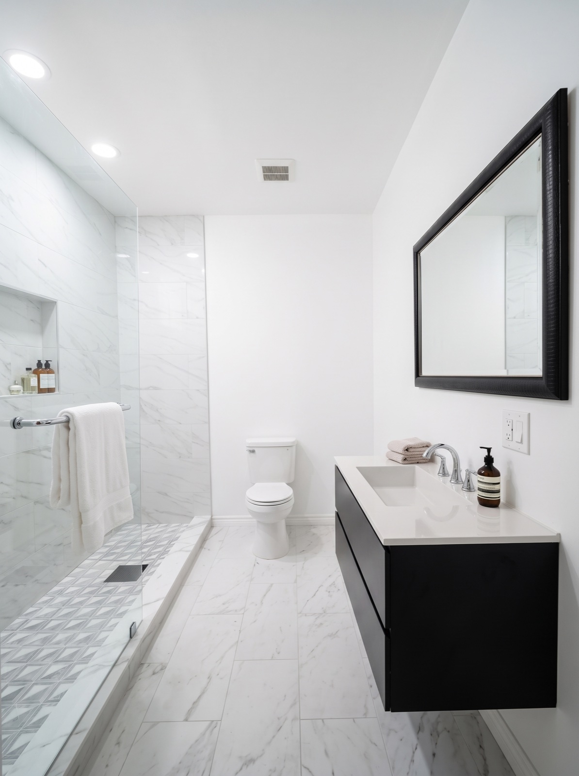 Modern marble bathroom remodel by Red Carpet with a glass walk-in shower and floating vanity