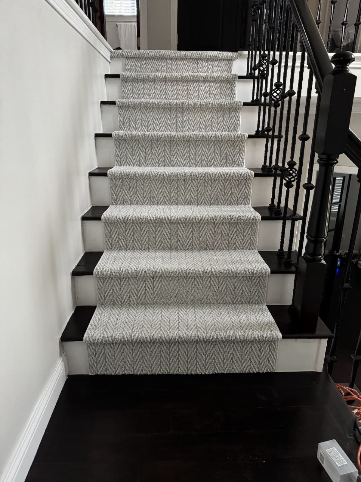 Gray herringbone carpet stair runner with black balusters