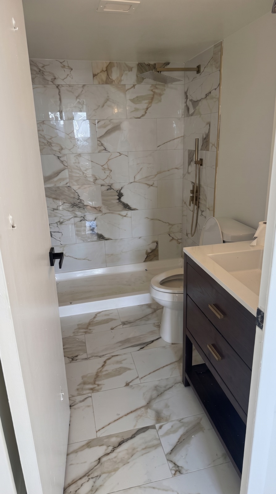 Bathroom with a marble tub-and-shower surround and dark vanity