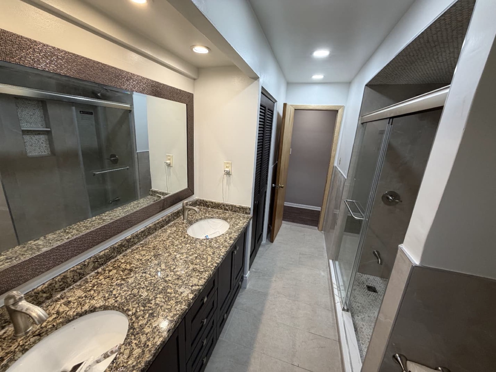 Bathroom with double vanity, granite counter, and glass shower