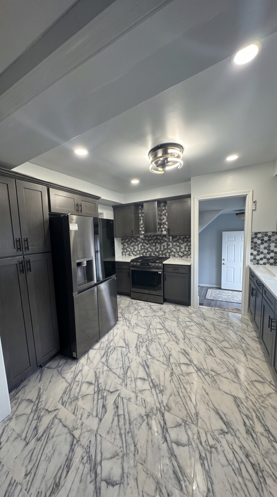 Gray-cabinet kitchen with black stainless appliances and tile backsplash