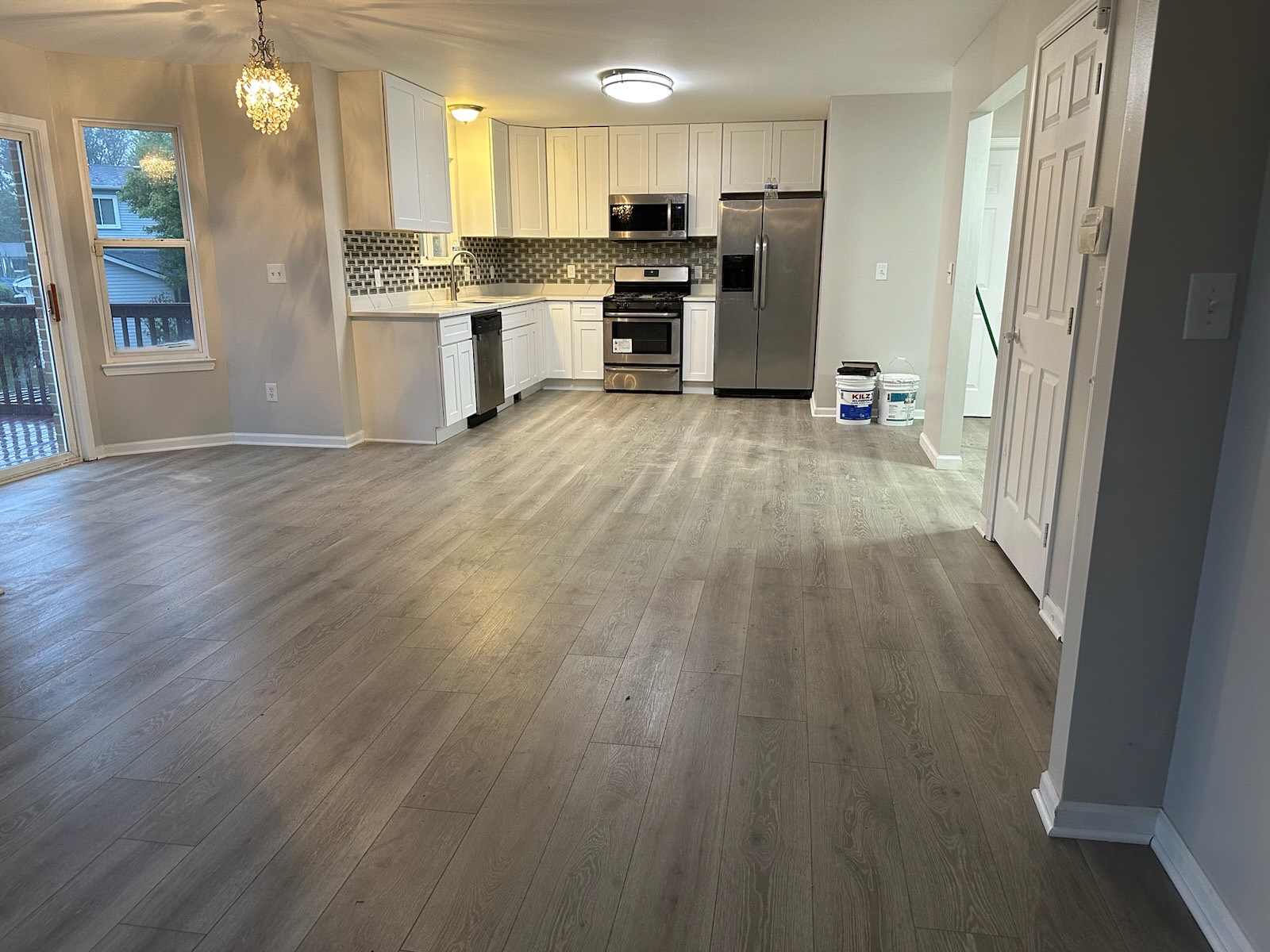 Open-concept kitchen with white cabinets and gray luxury vinyl flooring