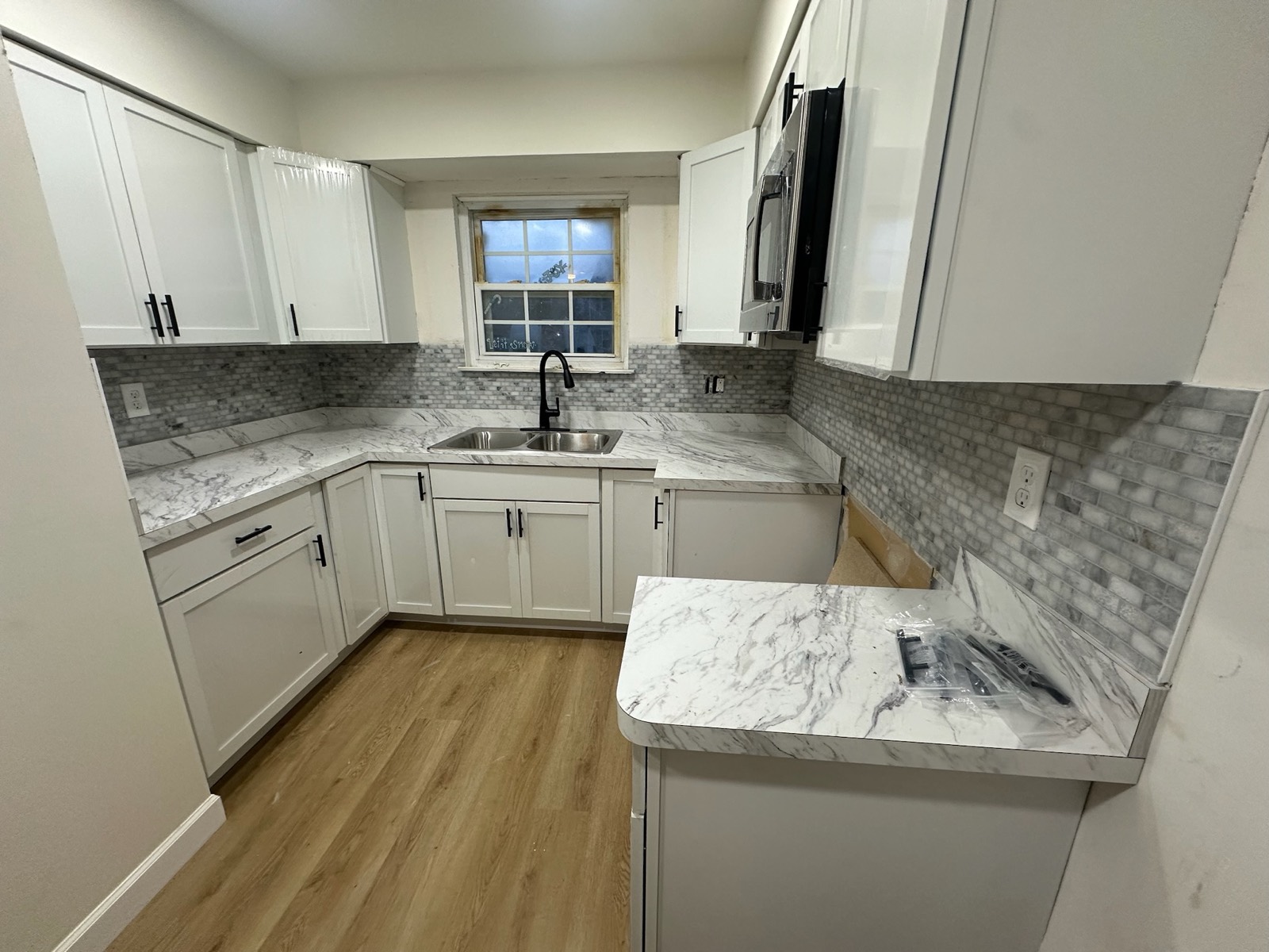 Kitchen with white shaker cabinets, marble-look counters, and mosaic backsplash