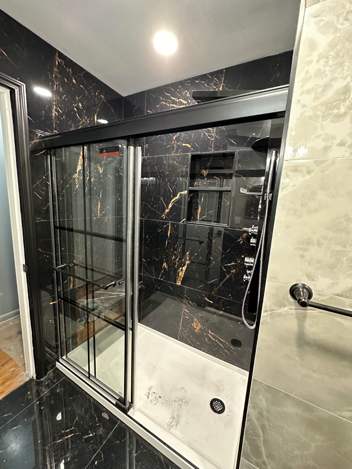 Black marble shower with sliding glass door