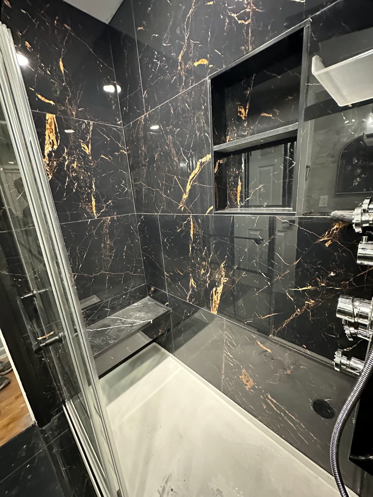 Black and gold marble tile shower with glass door